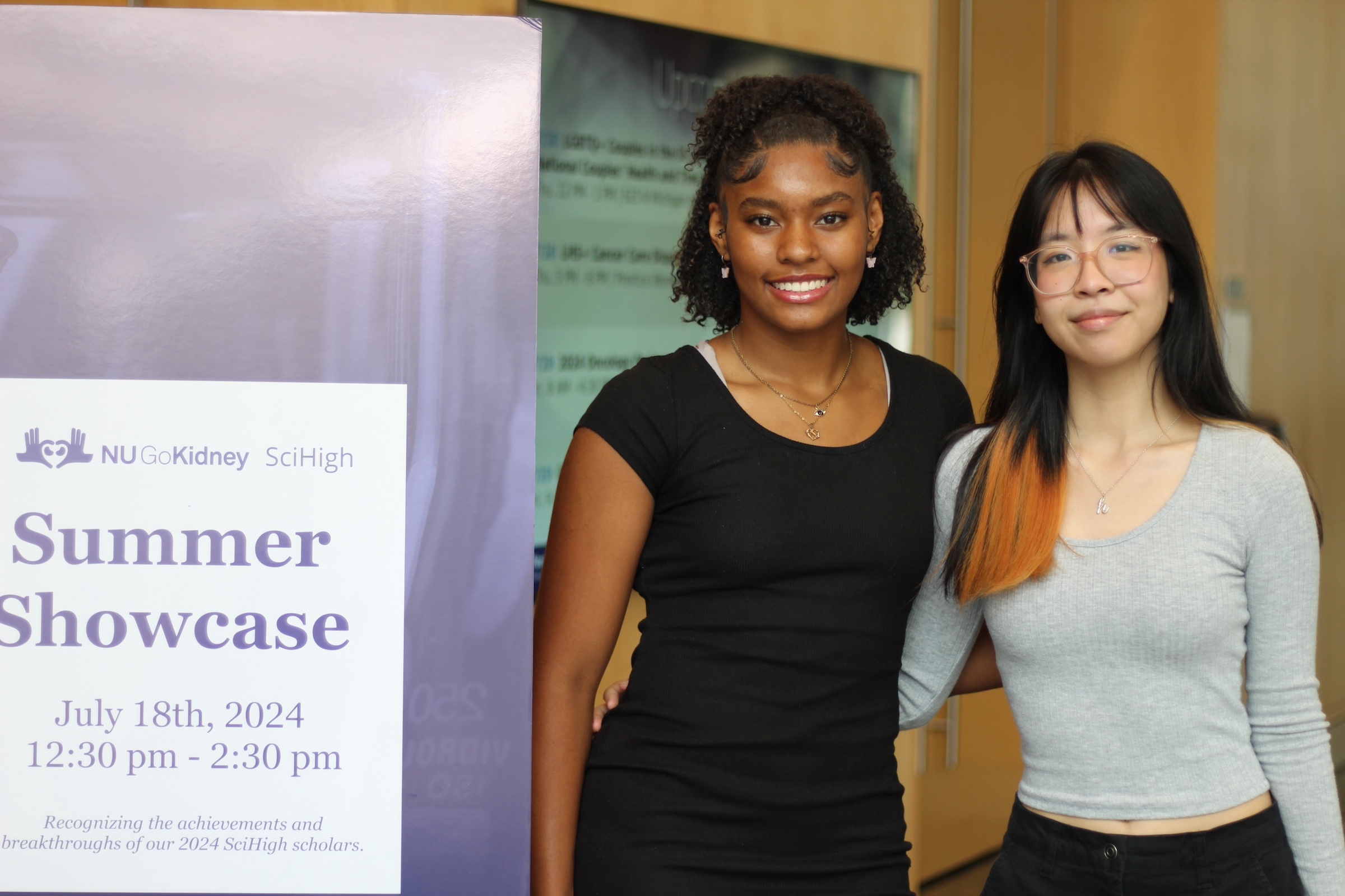 Holy Trinity students Nayanah Mahone and Kim Le in front of showcase poster.